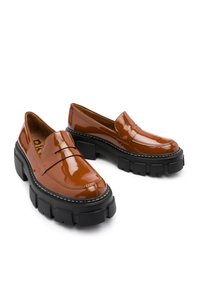 Mocasines de charol marrón con suela negra gruesa, que presentan un diseño clásico de tira tipo penny y detalle de costura a lo largo del borde.