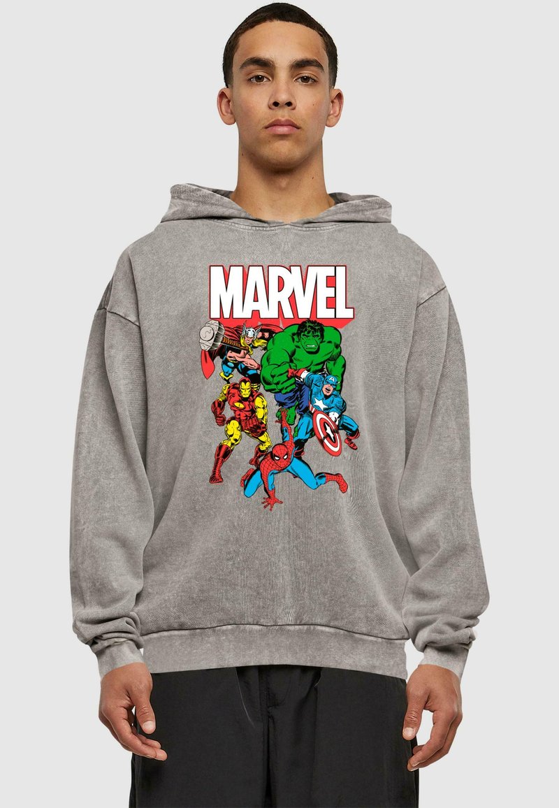 Siva dukserica s kapuljačom s šarenim Marvel grafičkim prikazom likova poput Hulka, Thora i Spider-Mana. Materijal izgleda mekano; dizajn je ležeran.