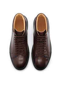 Rjavi usnjeni visoki športni copati z gladko teksturo, okroglim sprednjim delom, z zasnovo šestih izvrtin za vezalke in kontrastnim svetlo bež podlogo.