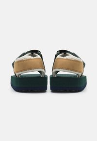 Sandal cu un design multicolor, având o parte superioară texturată și bretele verzi, bej și negre, plus o talpă groasă în verde și albastru închis.