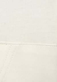 Helle Stofffarbe mit einem strukturierten Rippenteil über einer glatten, flachen Schicht, mit sichtbaren Nähdetails entlang der Naht.