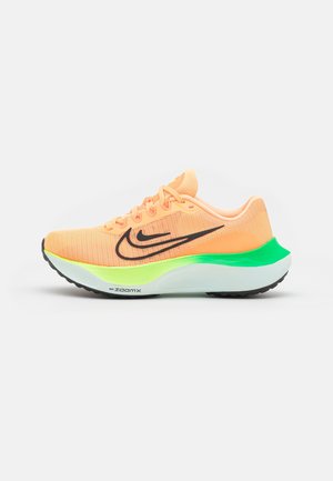 Chaussure de course Nike orange vif avec logo swoosh noir, semelle néon verte et blanche, et bande de roulement noire, présentée de profil sur fond blanc.