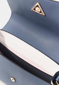 Borsa in pelle blu con finitura testurizzata, dotata di un interno in pelle bianca, hardware color oro e un dettaglio del logo triangolare.