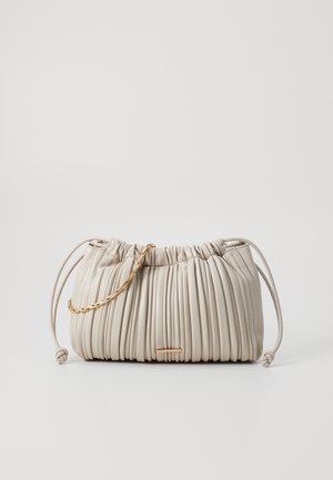 Sac à main plissé beige avec fermeture à cordon, anses en cuir nouées et une petite chaîne dorée posée sur le devant en haut.