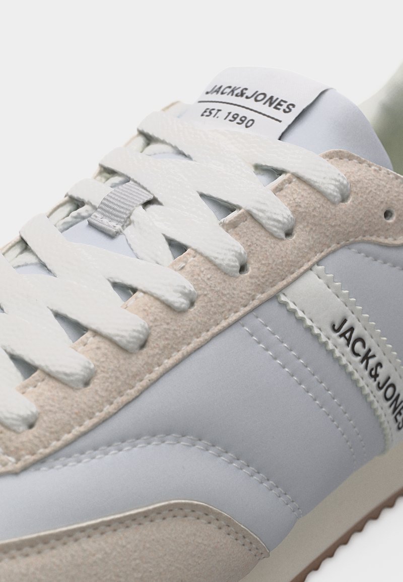 Zapatilla blanca y beige de Jack & Jones con cordones blancos, detalles de ante y etiqueta con el logo en la lengüeta y el lateral.