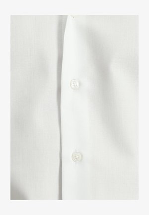 Camisa blanca de botones con tela texturizada, con dos botones visibles en el centro, mostrando un diseño limpio y clásico.