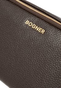 Clutch bag in pelle marrone dalla texture con zip dorata e logo "BOGNER" embossato sul davanti. Finitura liscia, forma compatta.