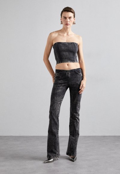 Mustmust tumed crop top ja flared teksad mustast denimist. Tekstuuriga kangas kerge kulumisega. Hõbedased terava ninaga kontsad täiendavad riietust.
