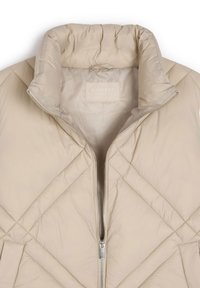 Beżowa pikowana kurtka puchowa z wysokim kołnierzem i zapięciem na zamek. Posiada ukośne przeszycia oraz miękką, gładką powierzchnię. Widoczna etykieta wewnętrzna.