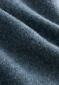 Donkerblauwe stof met een zachte, donzige textuur en een subtiel patroon van variërende dichtheid en golfachtige plooien.
