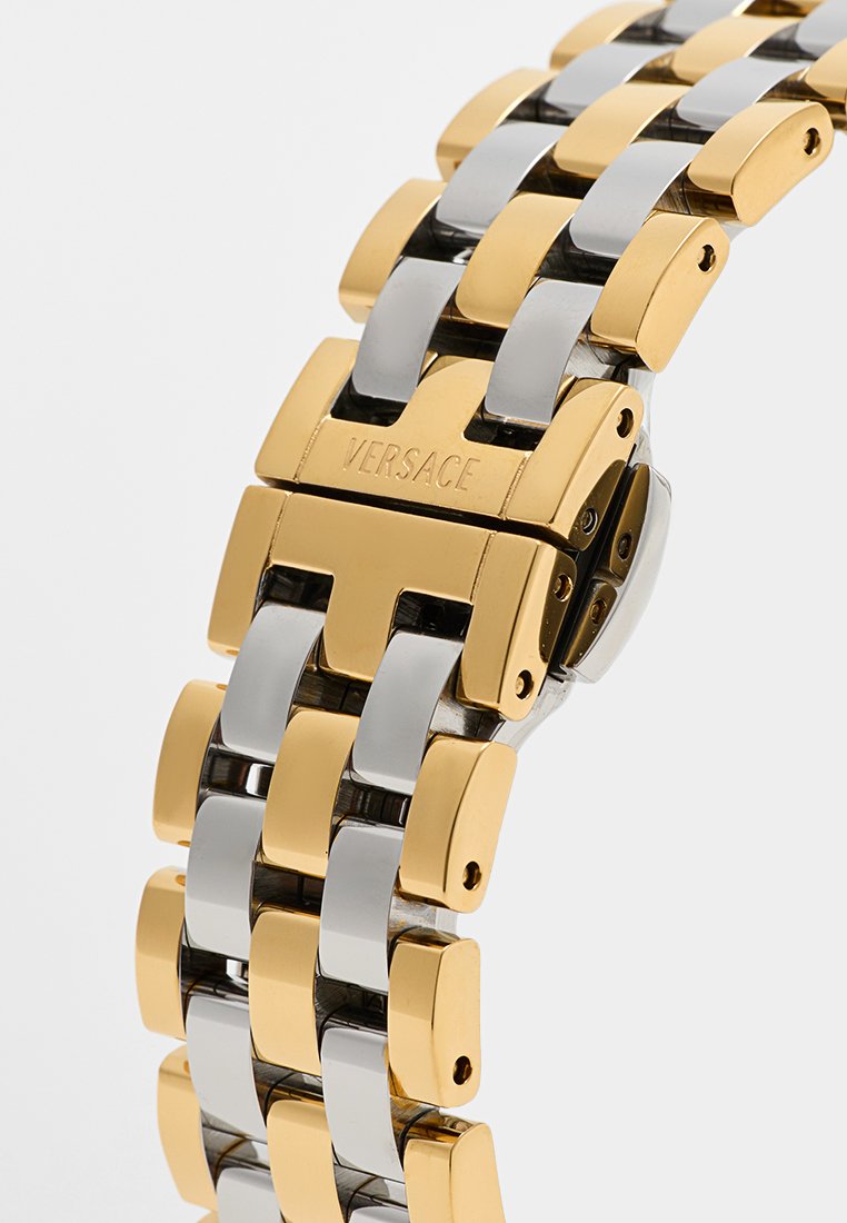 Gold- und Silberarmbanduhr aus Metall mit ineinandergreifenden Gliedern, präsentiert mit einem polierten Finish und einem Verschluss, der mit "VERSACE" gekennzeichnet ist. Elegantes Design.