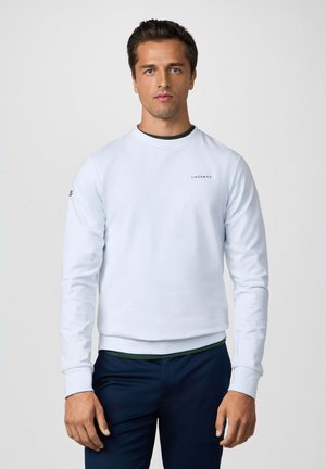 Hellblaues Sweatshirt mit langen Ärmeln, rundem Ausschnitt und geripptem Bund. Verfügt über ein kleines "Hackett"-Logo auf der Brust und einem grünen Akzent.