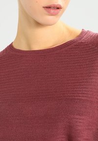 Maglione a maniche corte color bordeaux con un motivo a maglia testurizzato, scollatura rotonda e una vestibilità ampia, che mette in mostra un aspetto di tessuto liscio.