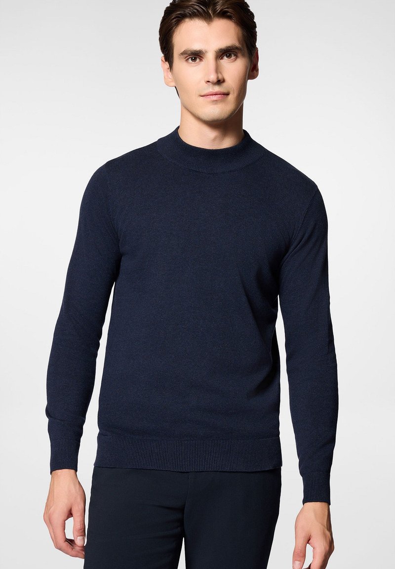 Granatowy sweter z dzianiny z wysokim kołnierzem i długimi rękawami. Żebrowane mankiety i dół, gładka tekstura oraz dopasowany fason.