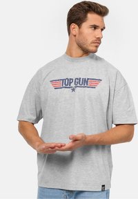 Šedé bavlněné tričko s grafikou "TOP GUN" se červenými křidélky a tmavě modrým obrysem, kulatým výstřihem a krátkými rukávy.