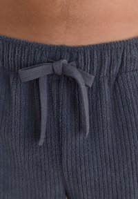 Dark gray ribbed lounge pants with an elastic waistband and bow tie detail. The fabric appears soft and textured.