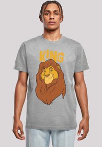 Sivi pamučni majica sa grafikom lava u smeškastoj i žutoj boji, sa natpisom "Kralj" iznad slike u podebljanom žutom fontu.