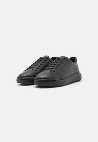 Sneakers in pelle nera con punta arrotondata, lacci piatti e suola in gomma. Texture liscia con cuciture minime e design a profilo basso.