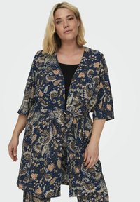 Gėlėmis raštuotas kimono, pagamintas iš lengvos medžiagos, turintis tamsiai mėlyną foną, ilgus rankovės ir dirželiu juosmeniui, leidžiančiu reguliuoti dydį.