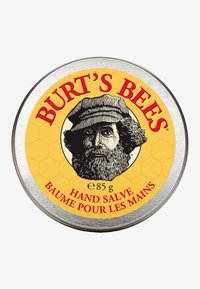 Barattolo rotondo in metallo di Burt's Bees Hand Salve, con un'etichetta gialla brillante che presenta un'illustrazione in bianco e nero di un uomo con la barba e un motivo esagonale.