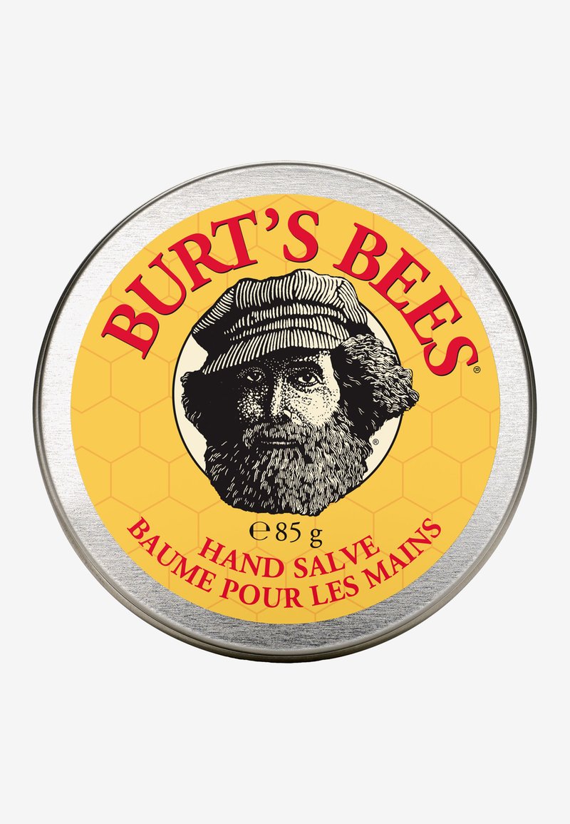 Rund metallboks med Burt's Bees håndsalve, som har en lys gul label med en svart-hvitt illustrasjon av en skjegget mann og et heksagonmønster.