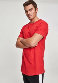 Crvena pamučna majica s okruglim izrezom, kratkim rukavima i ravnim krojem. Tekstura tkanine izgleda glatko, bez vidljivih uzoraka ili grafika.