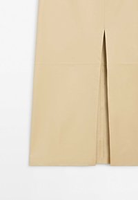 Jupe beige avec fente au centre devant, ourlet droit et texture lisse, montrée de la taille jusqu'en dessous du genou.