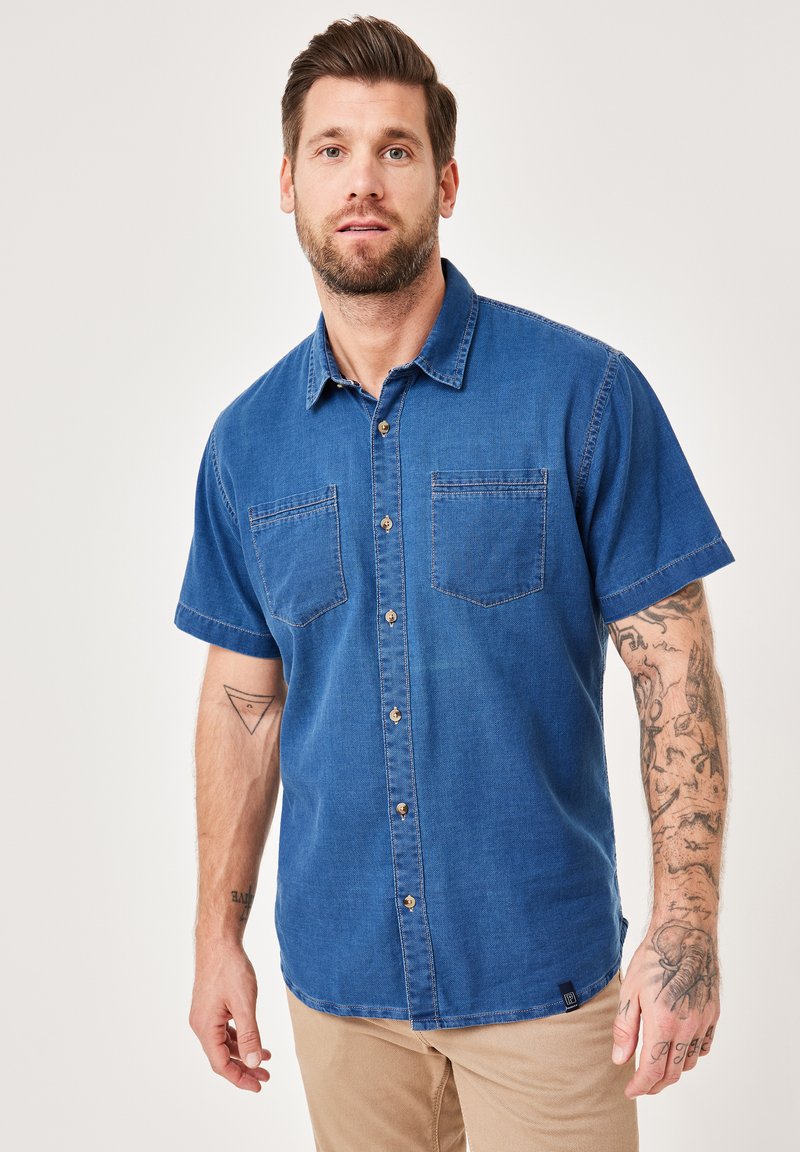 Kurzarm-Denimhemd in blauer Farbe, mit zwei Brusttaschen, Knopfleiste vorne, weicher Textur, kontrastierenden Nähten und einem kleinen Logodetail am Saum.