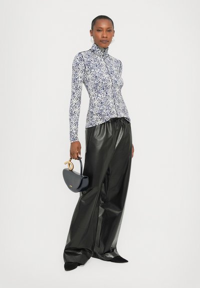 Long-sleeve, fitted turtleneck top with navy and white abstract print, paired with high-waisted black leather pants and a small navy handbag.