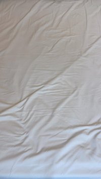 Jednobojni bijeli plaht sa vidljivim nabora, napravljen od glatkog materijala, sa mekom teksturom i ujednačenom bojom kroz celinu.