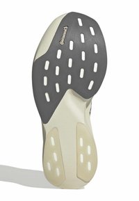 Schuhsohle mit einer grauen Gummifläche, die ein strukturiertes Muster aufweist, weißen Akzentlöchern und einem beigen Abschnitt nahe den Kanten. Markenlogo vorhanden.