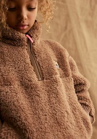 Giacca in pile marrone con zip a metà, dotata di tasca con cerniera e tirazip rosa. Tessuto morbido e texturizzato con logo ricamato.