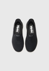 Čierne slip-on tenisky s priedušným sieťovaným zvrškom, textúrovaným povrchom a hladkými podrážkami, na vnútorných podrážkach so značkou Skechers.