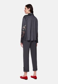 Shirt in dark gray with floral patterned sleeves, paired with matching gray trousers rolled at cuffs, and red flats. Smooth fabric texture.