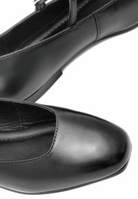 Czarne skórzane buty o gładkiej fakturze, zaokrąglonym czubku, niskim obcasie i bocznym pasie w designie. Posiadają przeszytą szew dla dodatkowego akcentu.