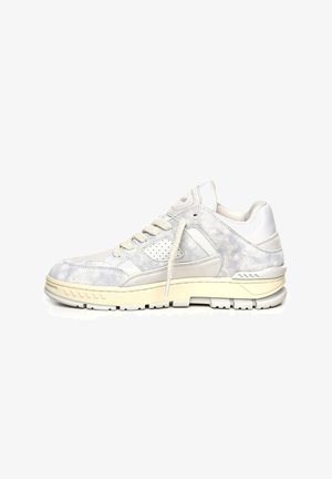 Zapatilla baja en ante blanco y gris claro con panel lateral perforado, cordones crema y suela gruesa color marfil.