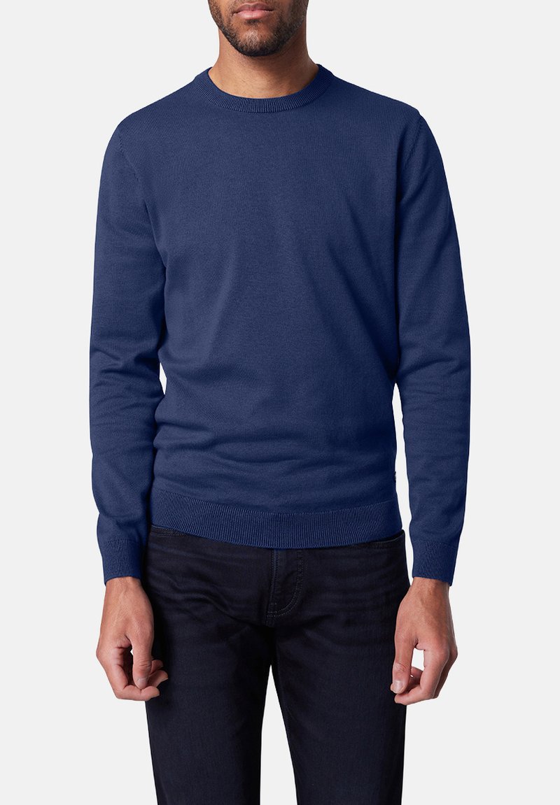 Navy blauer Strickpullover, Rundhalsausschnitt, lange Ärmel, gerippte Bündchen und Saum, weiche Textur, getragen über dunklen Jeans.
