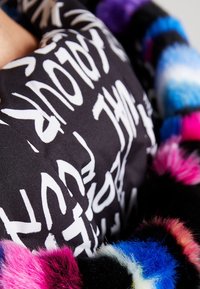 Zwarte stof met witte abstracte tekstopdrukken, met een fuzzy meerkleurige accent in roze, blauw en zwart langs de rand.
