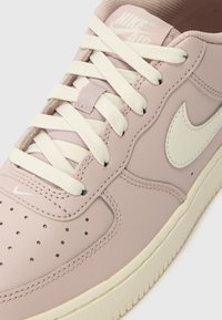 Rosa lær Nike Air sneakers med kremfargede lisser og swoosh, med perforert tå og beige gummisåle.