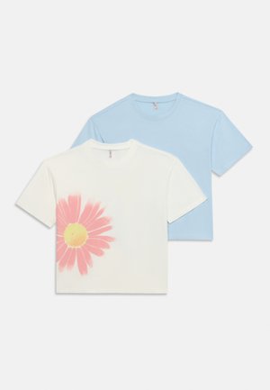 Zwei gefaltete T-Shirts mit kurzen Ärmeln und Rundhalsausschnitt, eines hellblau und eines weiß mit einem großen pink-gelben Gänseblümchen-Print auf der Vorderseite.