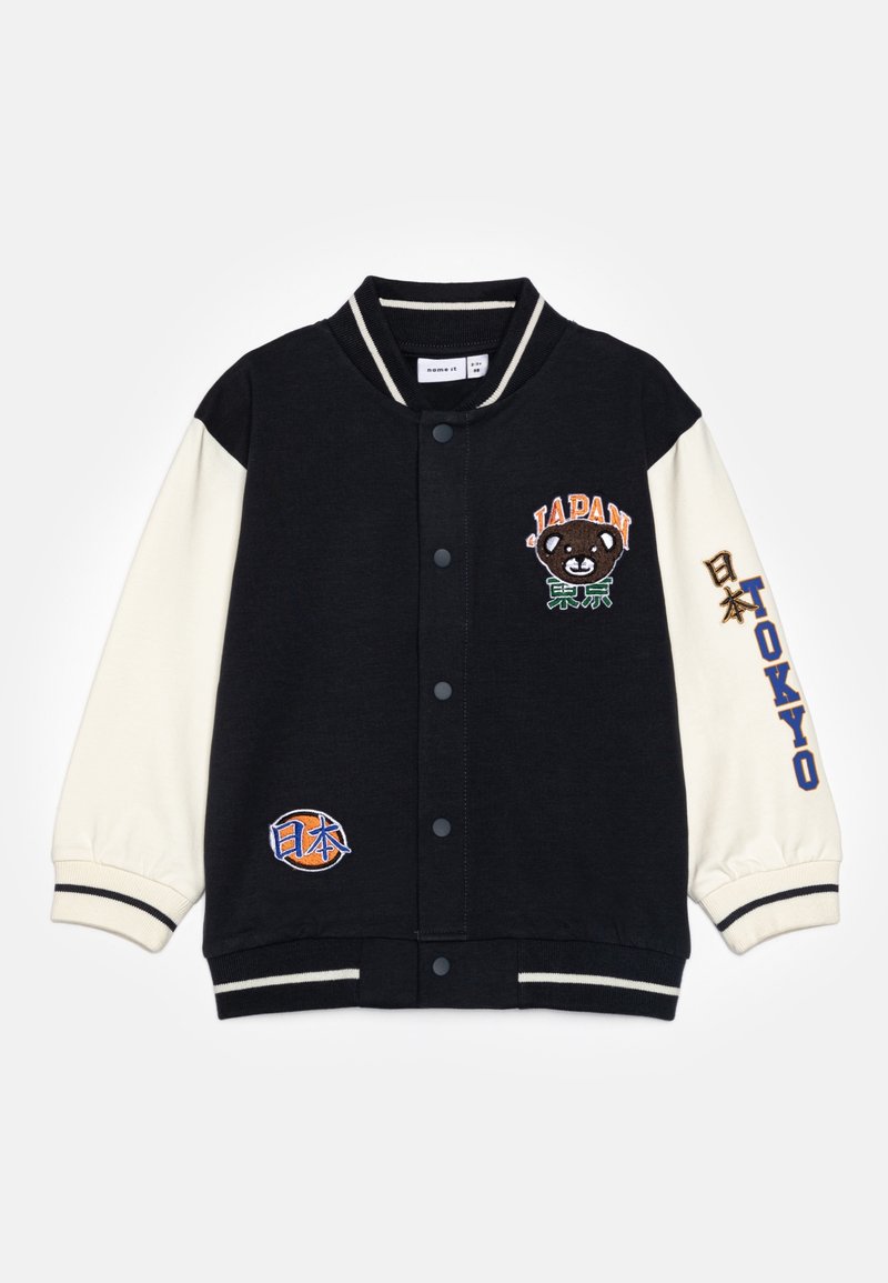 Veste varsity noire et crème avec broderie "Japon" et design d'ours, patch de basketball et poignets rayés. Fermeture par bouton et ourlet côtelé.