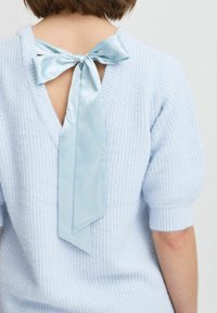 Hellblau gestrickter Pullover mit strukturierter Oberfläche, ausgestattet mit einem tiefen V-Ausschnitt, der mit einem satinartigen, hellblauen Band gebunden ist. Kurze Ärmel.