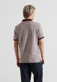 Korte mouwen polo shirt in gedempt kastanjebruin met horizontale strepen en een kastanjebruine kraag. Zachte stof met zijsplitten aan de zoom voor extra bewegingsvrijheid.