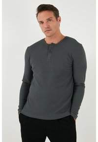 Szürke, hosszú ujjú henley póló, texturált kötött anyagból készült, kerek nyakkivágással és két gombos nyitással.