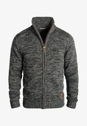 Grå strikket cardigan med høy krage, glidelås lukking og ribbestrikkede mansjetter. Har et strukturert mønster og en brun lærlogo som akcent.