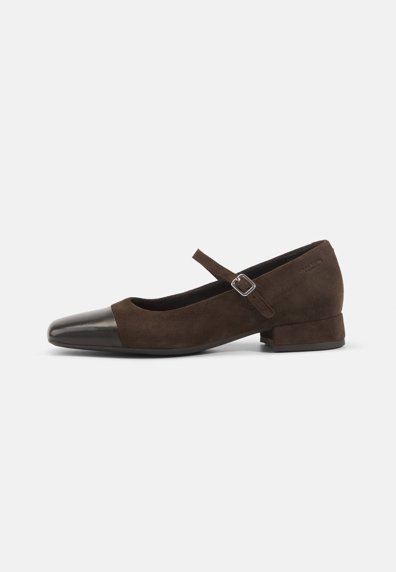 Chaussure Mary Jane en daim marron foncé avec bout rond noir, petit talon bloc et bride réglable à boucle.