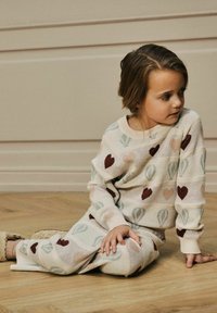 Strick-Loungewear-Set in Creme mit Mustern von Herzen und Heißluftballons in Pastellfarben. Weiche Textur und lässige Passform.
