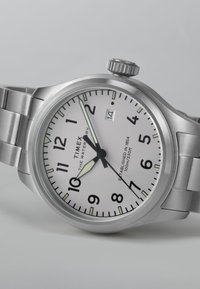 Edelstahlarmbanduhr mit weißem Zifferblatt, schwarzen arabischen Ziffern und einem Datumsfenster. Verfügt über eine glatte Lünette und leuchtende Zeiger.