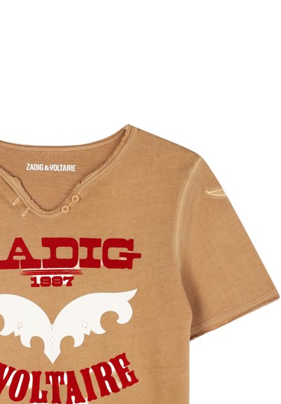 T-shirt in cotone marrone con colletto a girocollo, maniche corte, bordi sfrangiati e stampa grafica con dettagli rossi e bianchi sul davanti.