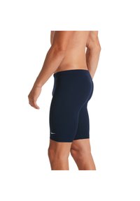 Shorts de sport navy en matériau extensible, offrant une coupe ajustée et un petit logo blanc sur le côté gauche.